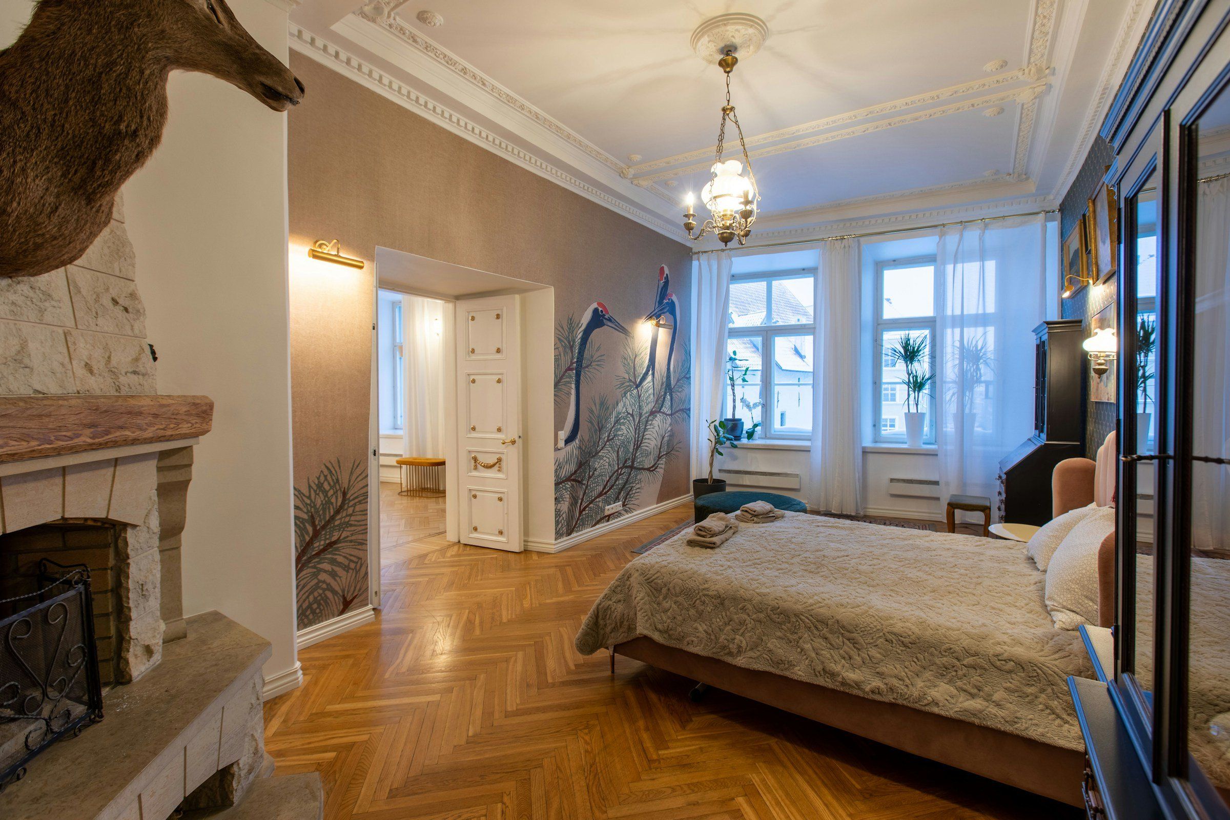 Schlafzimmer im Altbau mit Wandbild aus Kranichen und Kiefernzweigen hinter dem Bett